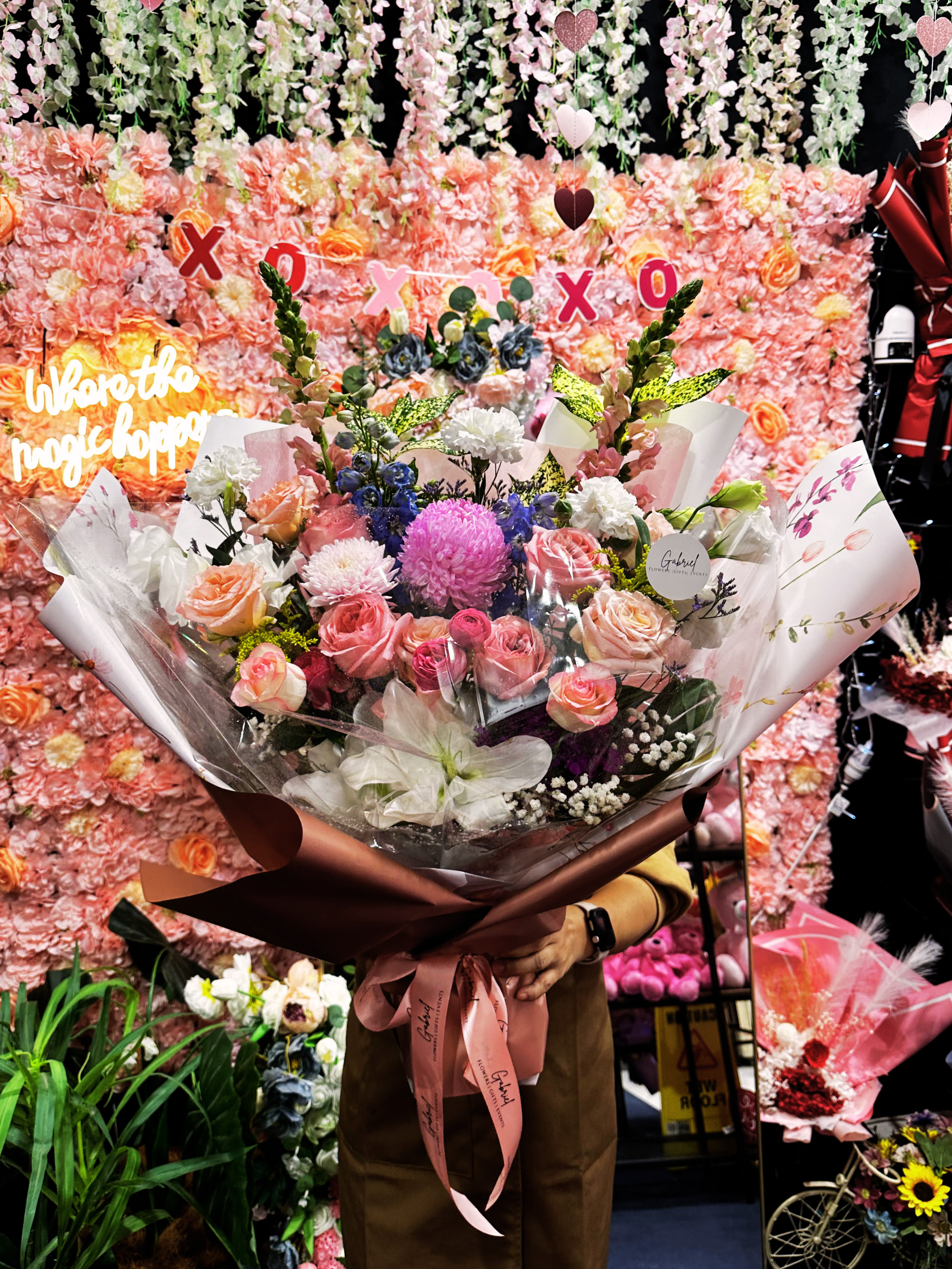 The Grand Romance Bouquet featuring 12 premium pink roses, seasonal flowers, and lush foliage beautifully handcrafted in an elegant bouquet.