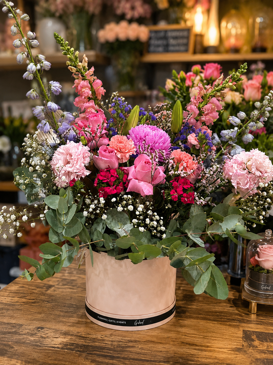 Bouquet of flowers with pink roses, mums, lisianthus, william, in a pink box on a flower shop